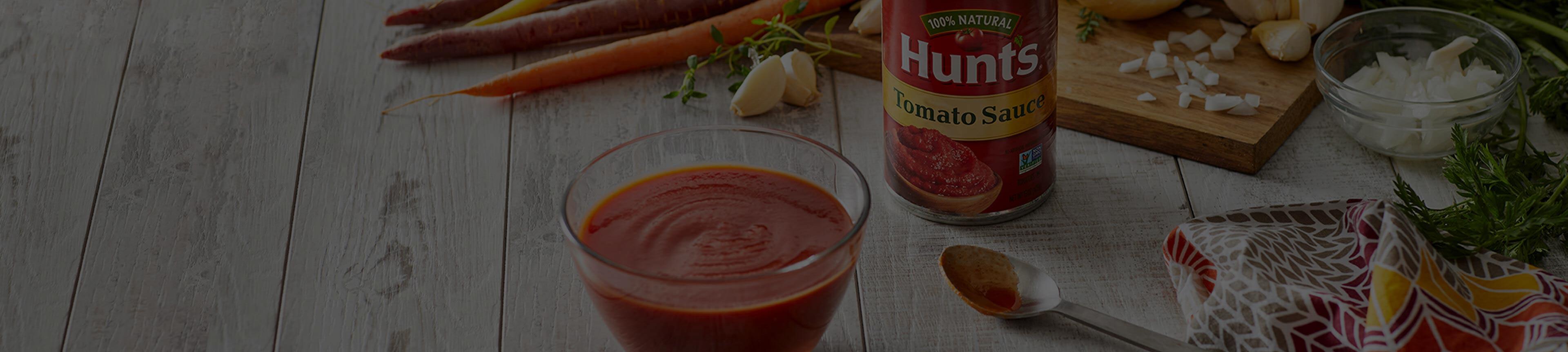 Hunt's Tomato Sauce in a bowl next to a spoon on a table