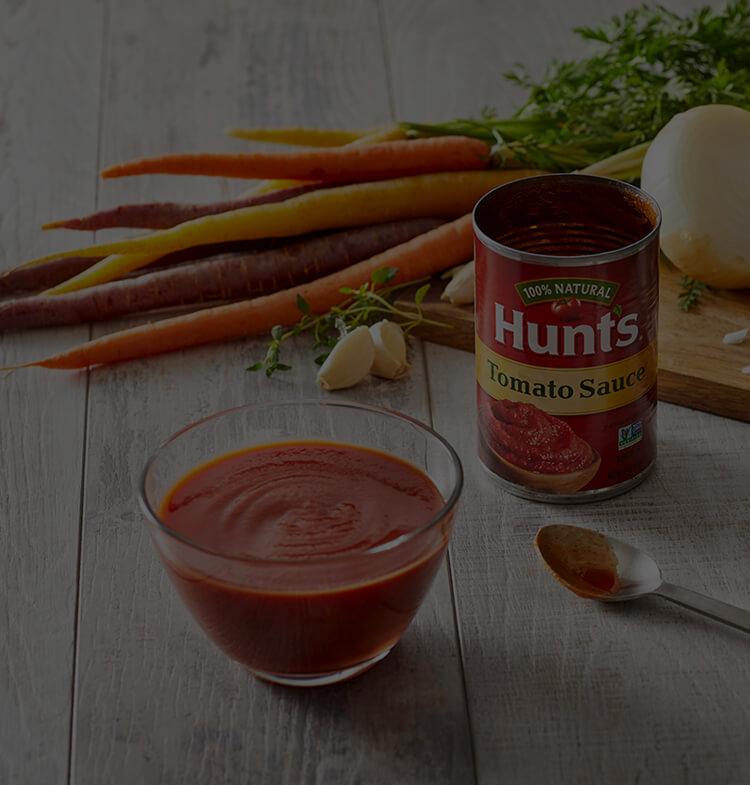 Hunt's Tomato Sauce in a bowl next to a spoon on a table